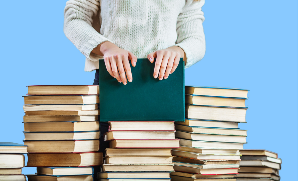 girl hands on the stack of books on blue background